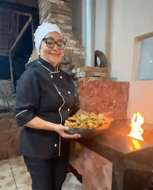 Chef sirviendo comida casera junto a la cocina