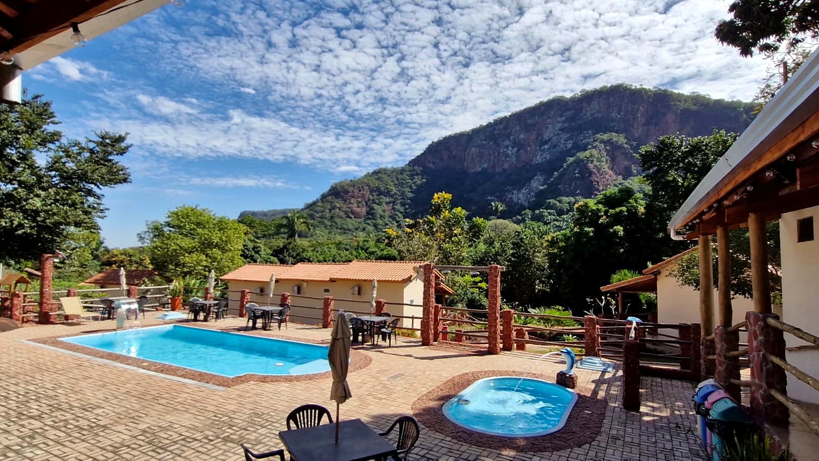 Adult and children’s pools with deck, tables, and Morro do Paxixi in the background.