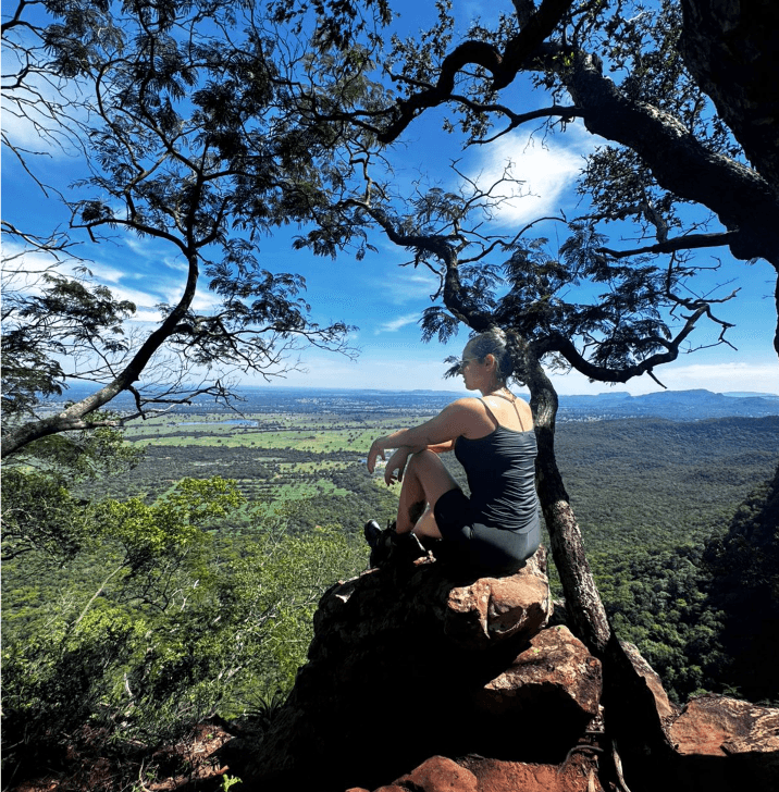 Guest looking over a tree-lined valley from a stone viewpoint.